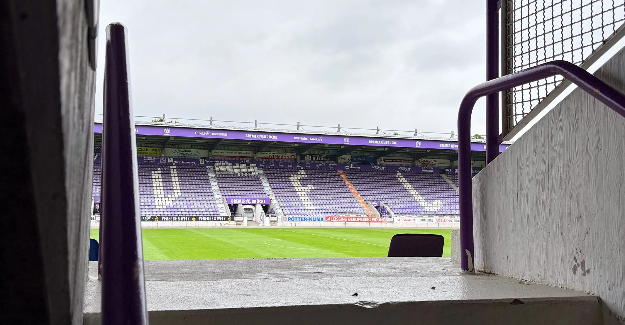 Stadiontour: Blick vom Aufgang auf die lila Sitzreihen im Stadion. Anteilsübertragung Meilenstein durch Stadiontour.